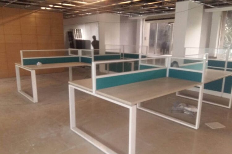 Face-to-face seating workstation with glass partition and sky-blue fabric screen, supported by MS square legs.