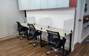 Office desk with cabinet, ergonomic chairs, and glass partitions for privacy.