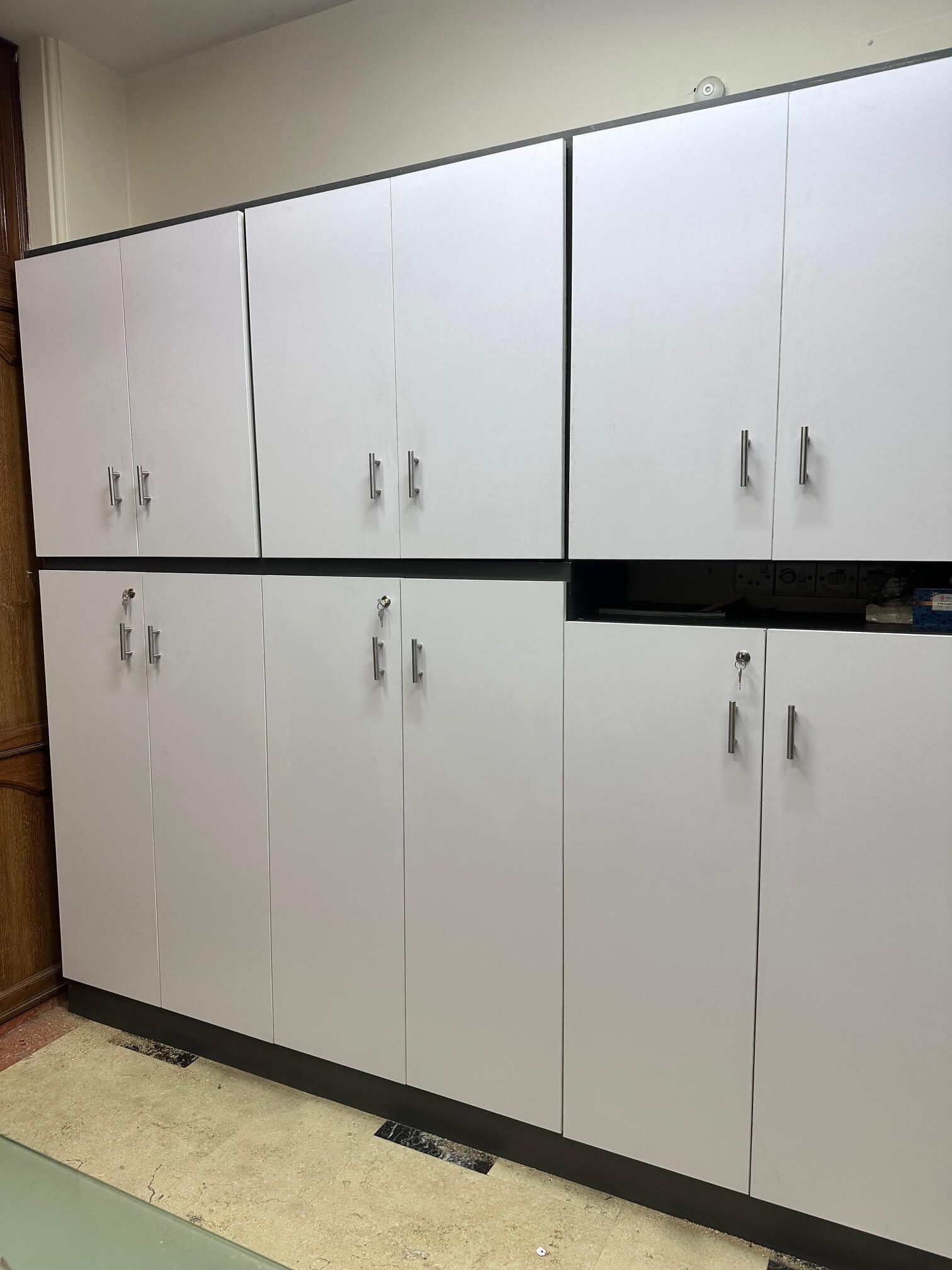 Full-height storage cabinet with multiple white compartments and modern handles, designed for secure office organization.