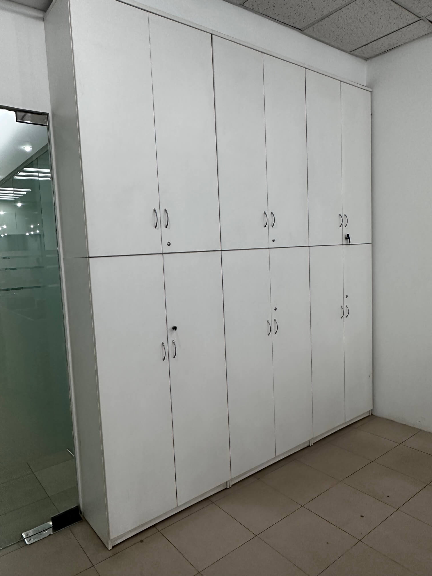 Full-height white storage cabinet with multiple locking compartments for secure office organization.