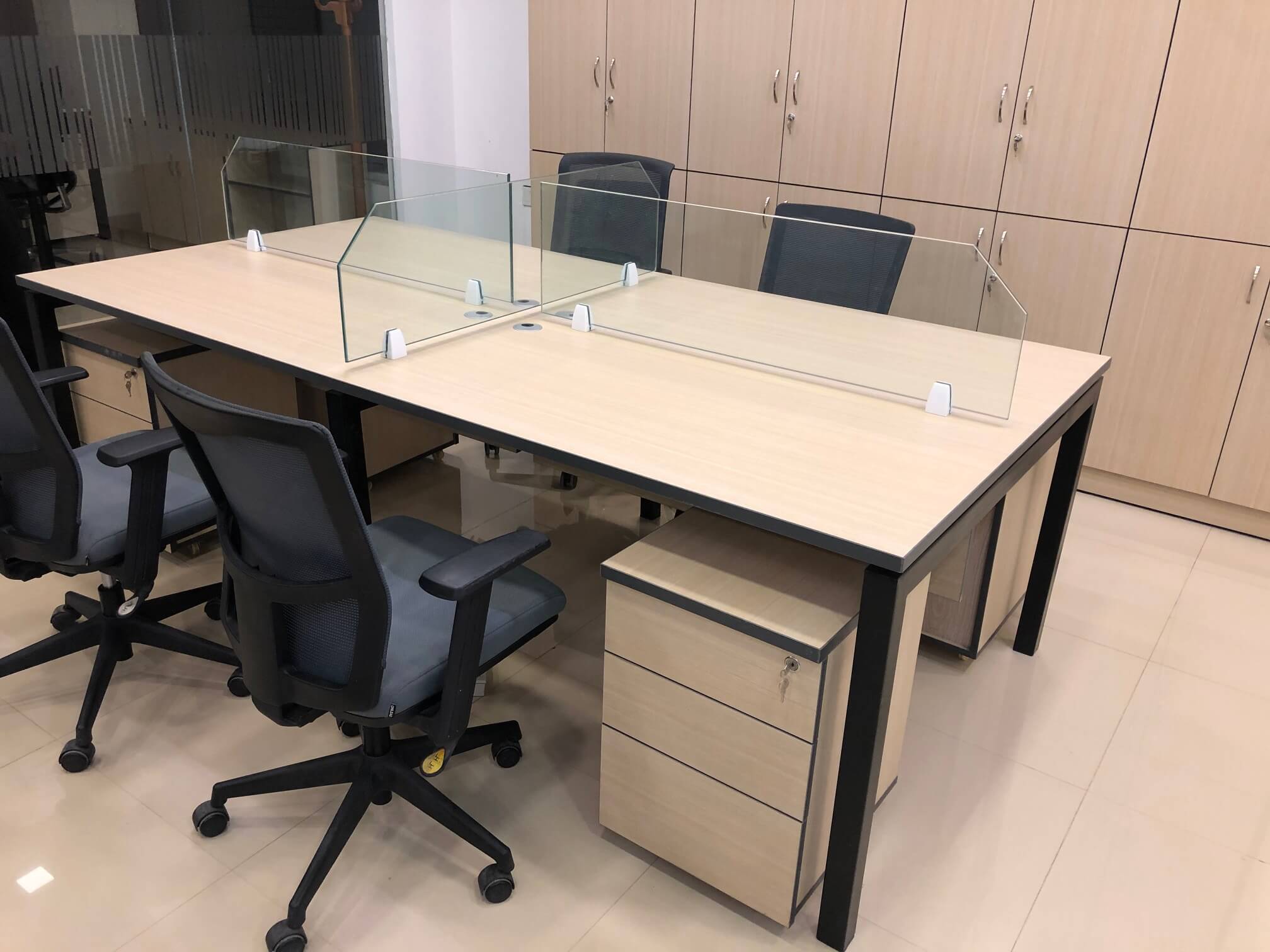 Modern office workstation with glass dividers, ergonomic chairs, and full-height storage cabinets.