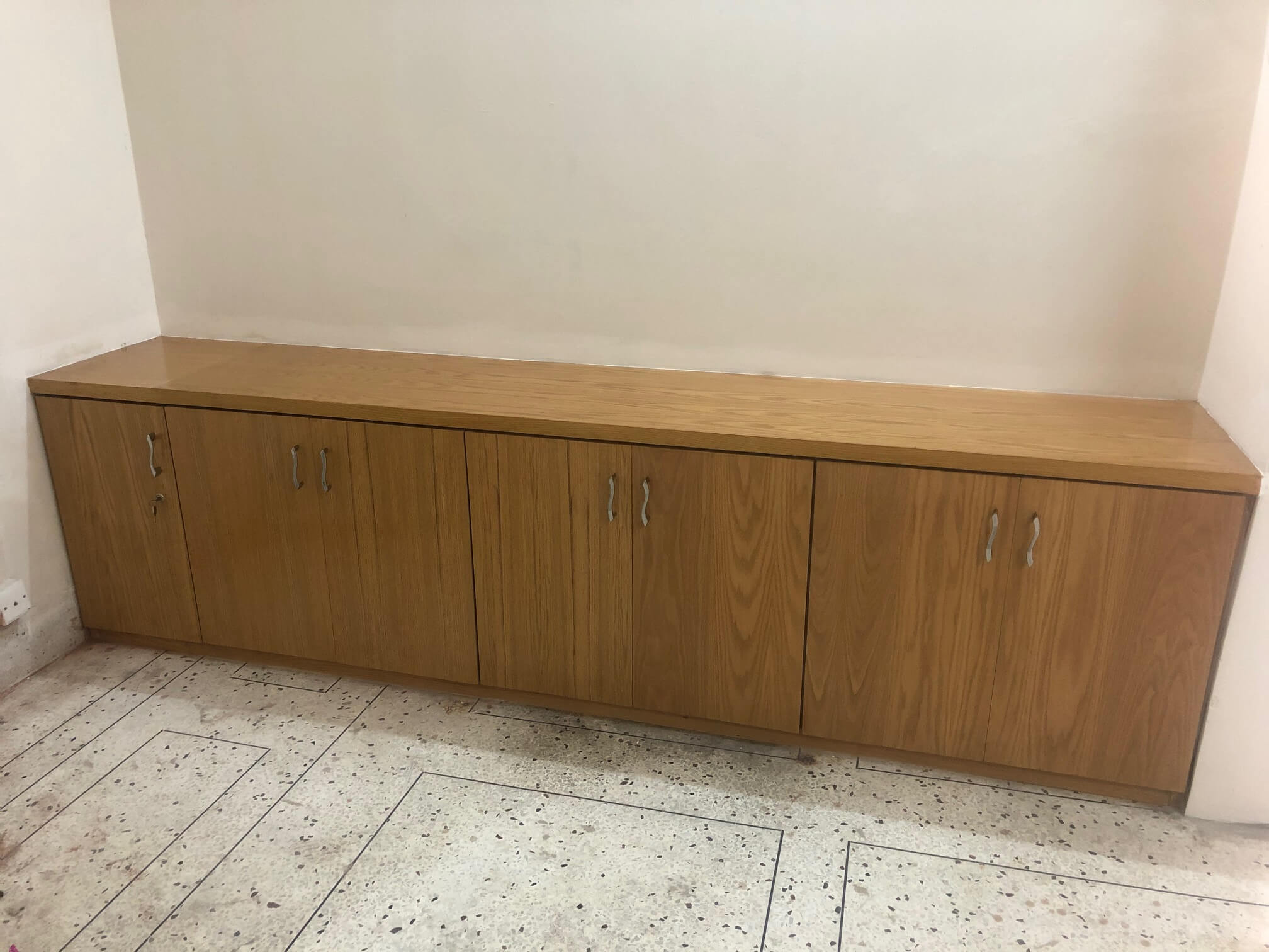 Low-height wooden storage cabinet with multiple drawers and a smooth top surface, designed for office or home use.