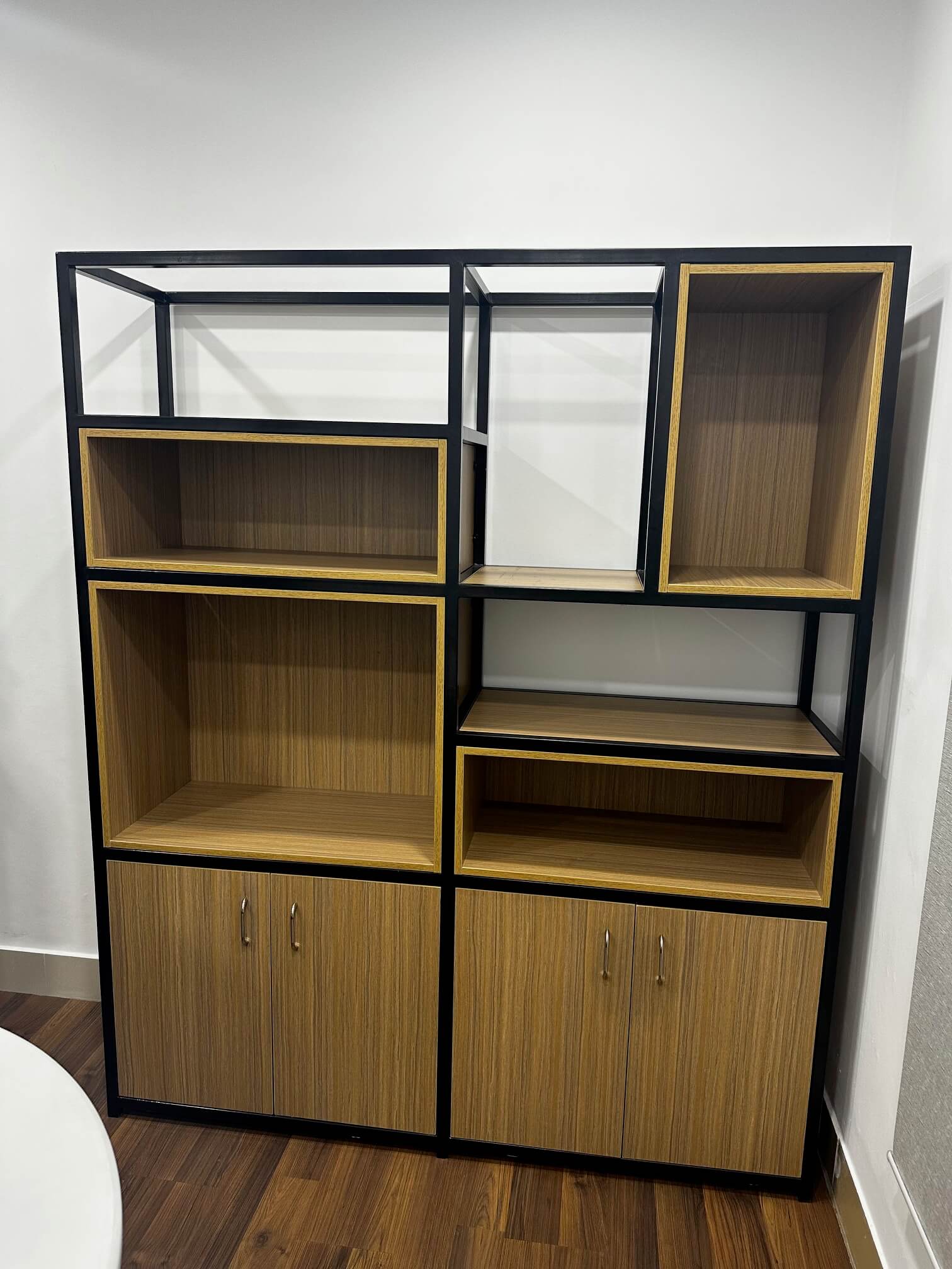 Modern metal frame storage cabinet with wooden shelves and doors, designed for contemporary office spaces.