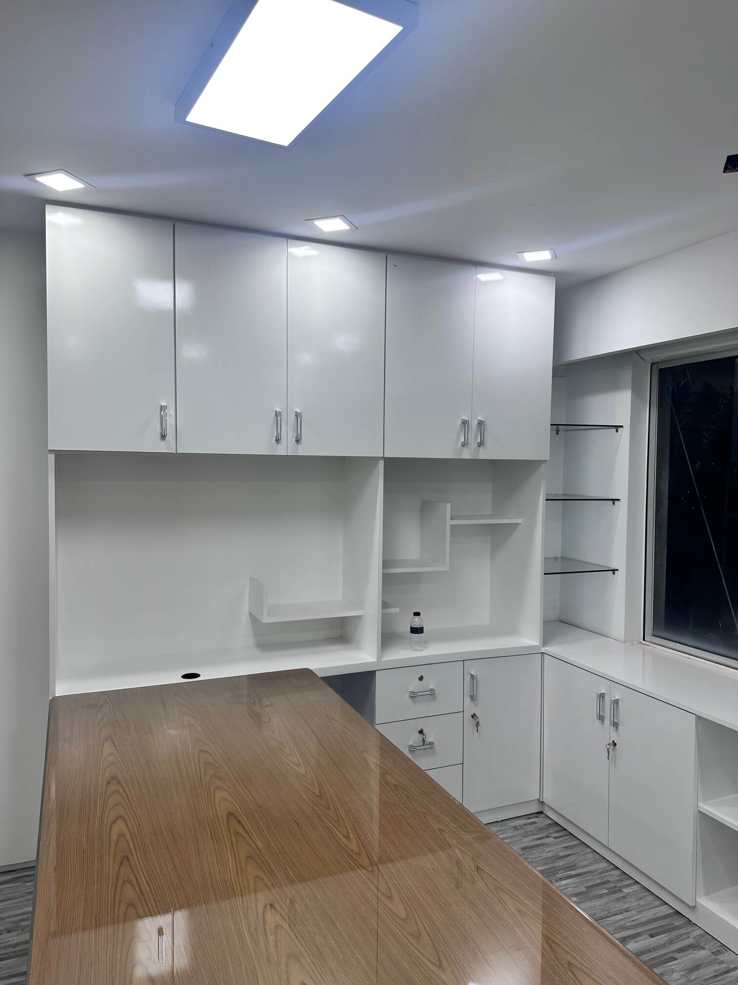 Modern white office cabinet with wooden work table and open shelving, designed for office organization and efficiency.