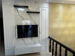 Elegant TV unit design with a marble wall and geometric patterned wall decor.